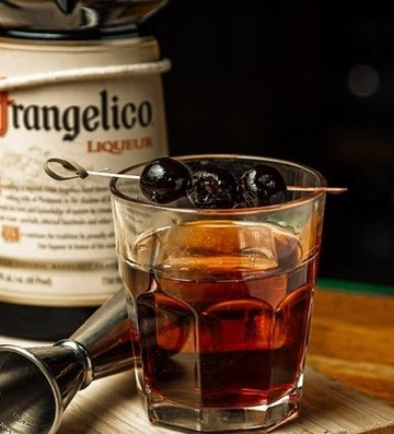 The Buffalo Amaro served in a rocks glass with skewered cherries, beside a jigger and a bottle of Frangelico at O'Pub.