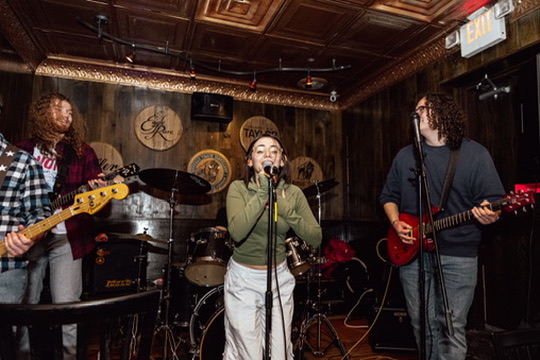 Bass, vocals and guitar on the O'Pub stage in front of the drum kit and the wood-panelled back wall.